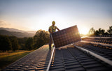worker installing solar panels at sunset